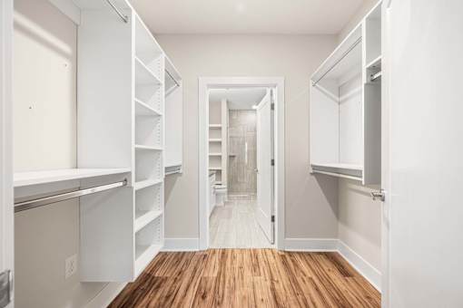 A white walk in closet with shelves and a doorway.