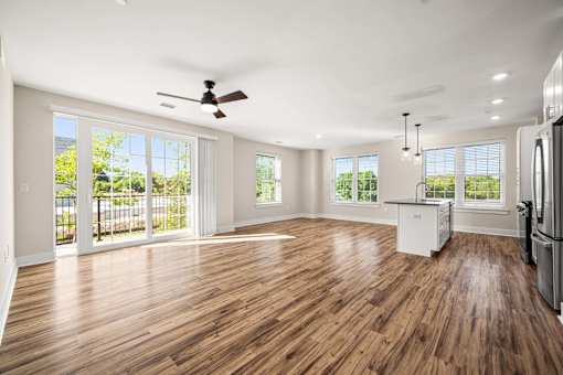 A spacious kitchen with wooden floors and a ceiling fan.