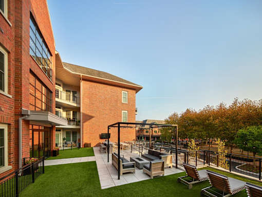 A modern outdoor seating area with a black metal pergola and benches.