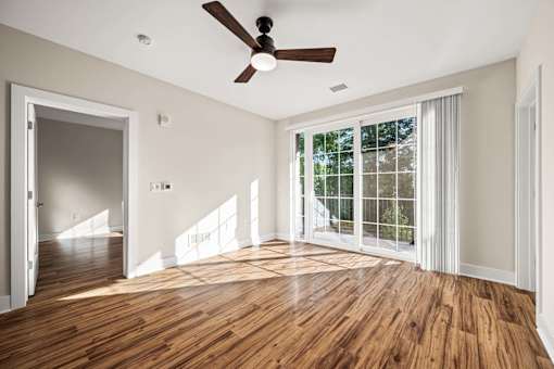 A room with a ceiling fan and a large window.