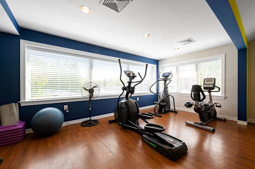 Cardio machines, a gym ball, and a fan at our state-of-the-art fitness center with many large windows and plenty of light.