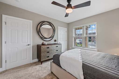 A bedroom with a bed, dresser, mirror, and window.