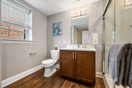 A bathroom with a toilet, sink, and wooden floors.