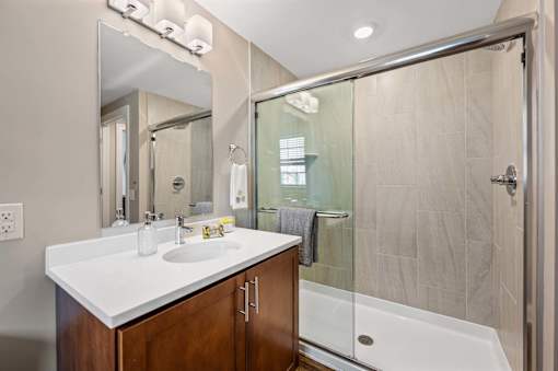 A bathroom with a white countertop and a walk-in shower.
