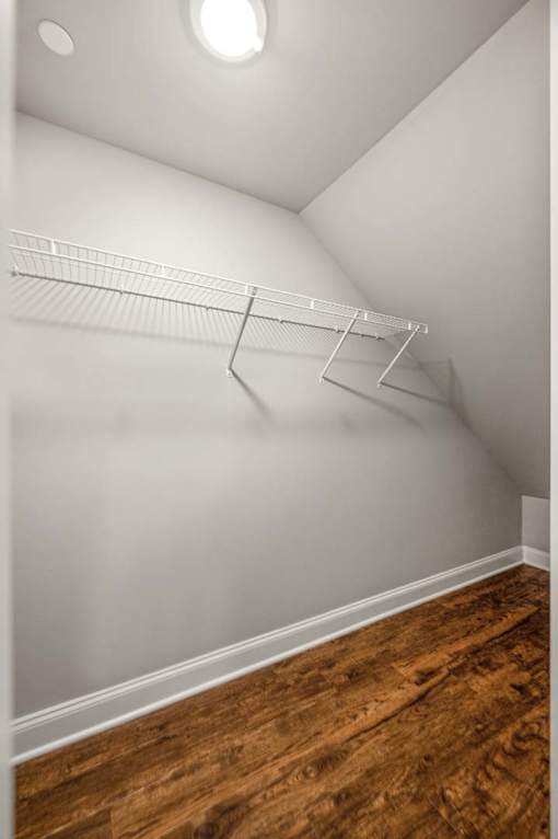 Empty room with a white wall and a wooden floor.