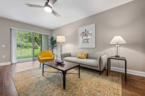 A living room with a yellow chair, a white couch, and a patterned rug.