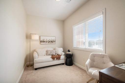A living room with a white couch, a chair, and a lamp.