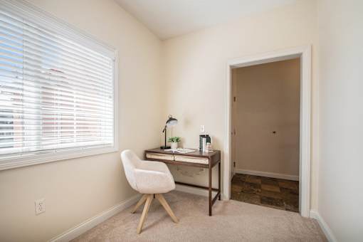 A room with a desk and chair by the window.