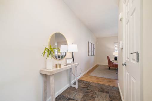 A hallway with a white door and a table with a plant on it.