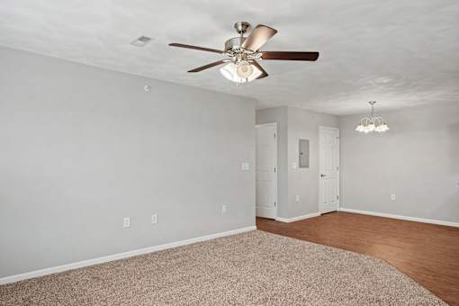 Northbrooke Commons Living room and entry way with ceiling fan, modern light fixture and both carpeted and vinyl plank flooring.