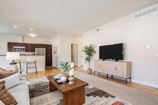 A living room with a white couch, a wooden coffee table, and a television.