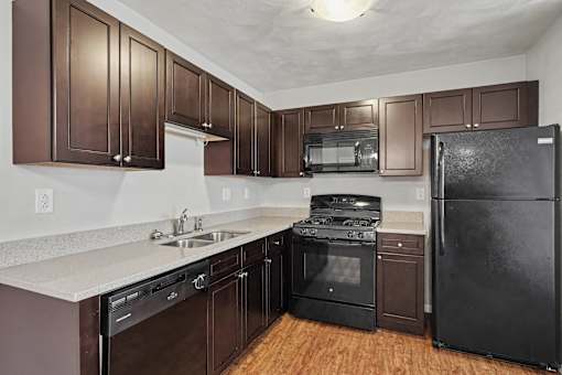 Northbrooke Commons kitchen with dark colored cabinets, black appliances and granite countertops
