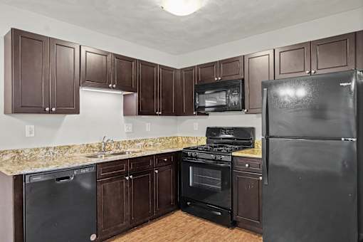 Northbrooke Commons kitchen with dark colored cabinets, black appliances and granite countertops