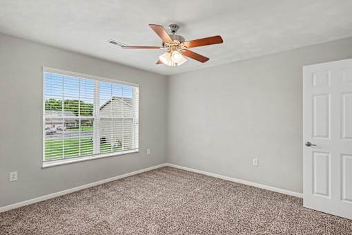 Northbrooke Commons bedroom with large windows, blinds, ceiling fan and plush carpeting