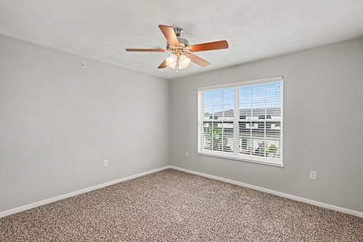 Northbrooke Commons bedroom with large windows, blinds, ceiling fan and plush carpeting