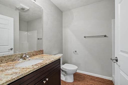 Northbrooke Commons bathroom with large mirror, granite countertop and dark cabinetry