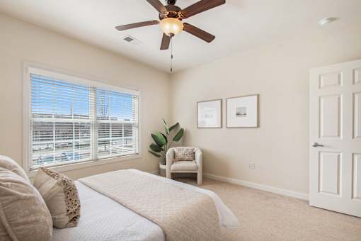 A bedroom with a bed, chair, and pictures on the wall.