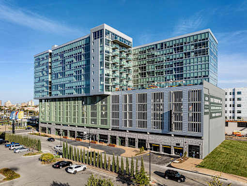 A modern glass and concrete building with cars parked in front. at One Foundry Way Apartments, St Louis, MO