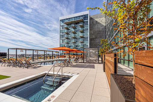 A modern pool area with a glass building in the background. at One Foundry Way Apartments, Missouri, 63110