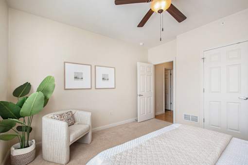 A living room with a white couch, a potted plant, and a ceiling fan.