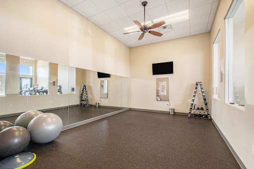 A room with a brown floor and a ceiling fan.