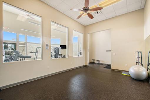 A spacious room with a ceiling fan and a large exercise ball on the floor.