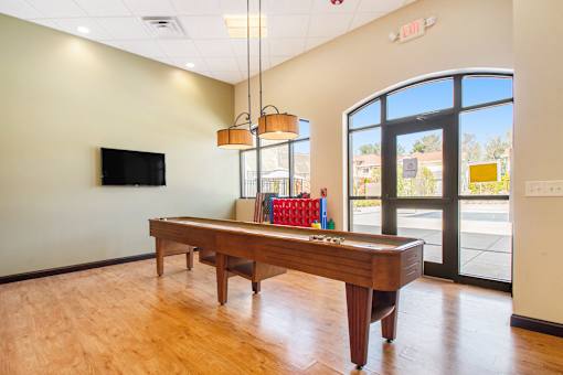 A room with a long table and a television on the wall.