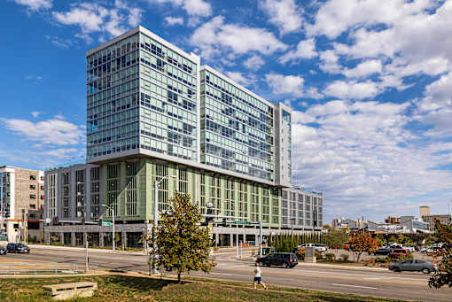A large glass building with a green roof stands in front of a cloudy sky. at One Foundry Way Apartments, St Louis, MO, 63110