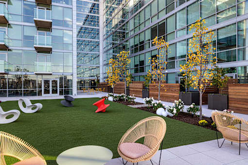 A modern outdoor seating area with wicker chairs and tables. at One Foundry Way Apartments, St Louis