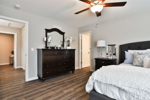 a bedroom with a bed and a dresser and a ceiling fan