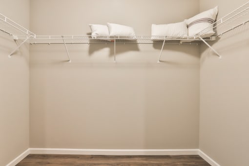 a room with a shelf with pillows on it and a wall with a closet