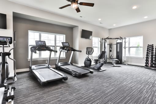a gym with treadmills and other exercise equipment and a ceiling fan