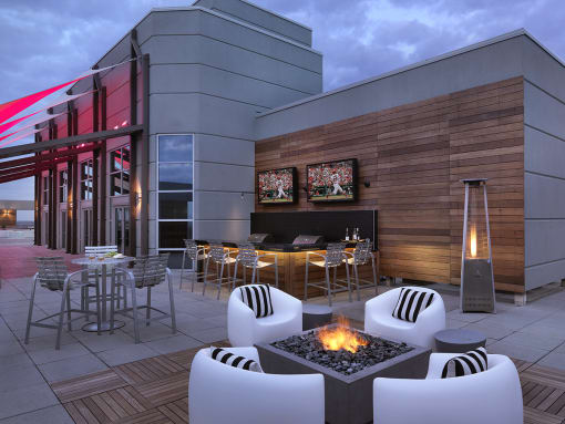 24th floor sky deck at dusk with conversation seating, fire pit, bar and two televisions  at Clayton On The Park, Clayton, Missouri