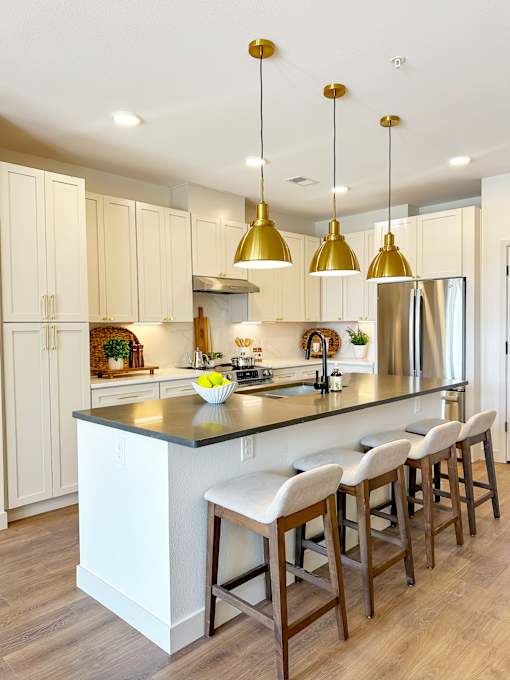 A kitchen with a white island and bar stools.