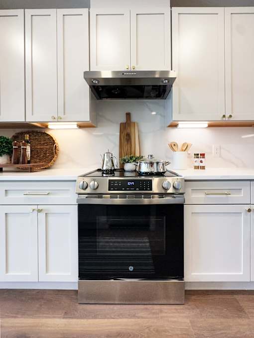 A modern kitchen with white cabinets and a stainless steel oven.
