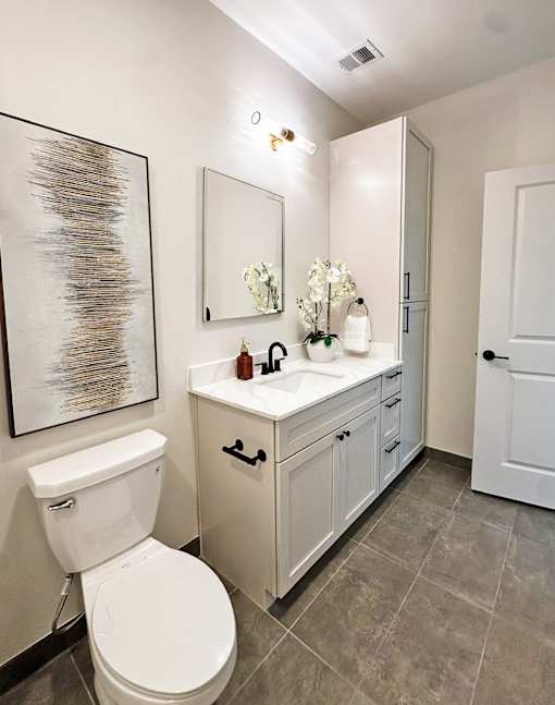 A bathroom with a toilet, sink, and a painting on the wall.