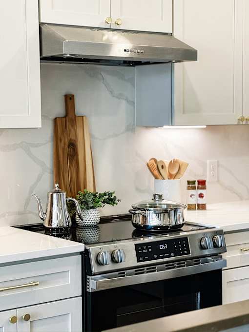 A modern kitchen with a stove, oven, and white cabinets.