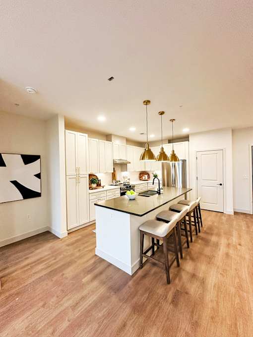 A kitchen with a white island and wooden floors.