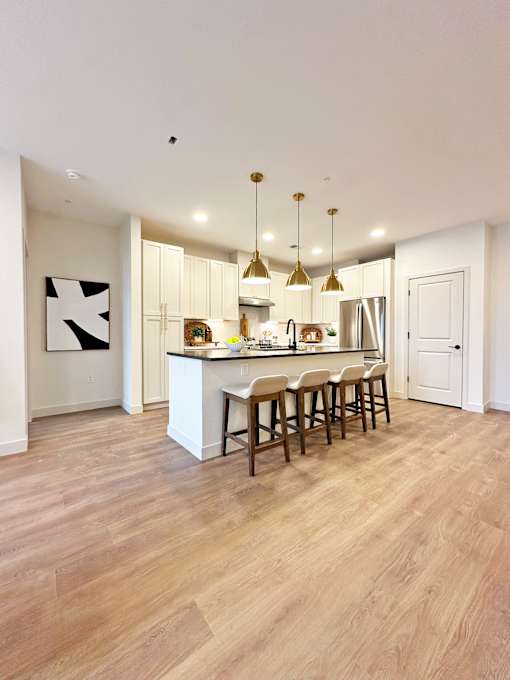 A kitchen with a white island and wooden floors.