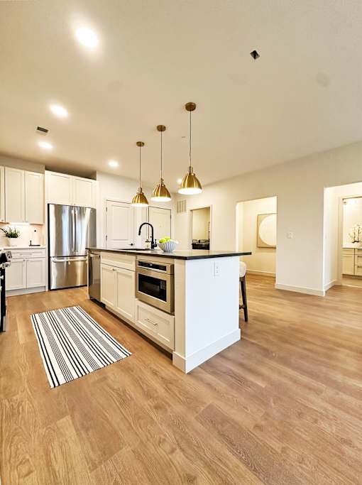 A kitchen with a white island and striped rug on the floor.