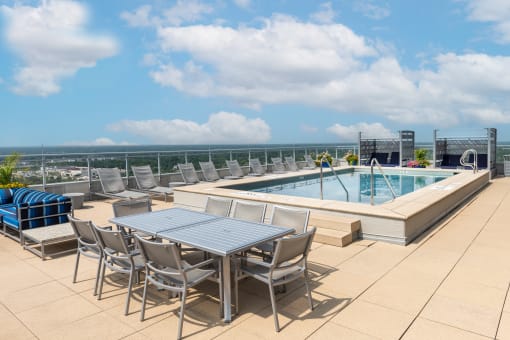 a pool and dining table on a rooftop patio with the ocean in the background at Two Twelve Clayton, Missouri, 63105