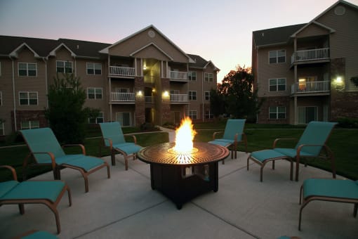 round gas firepit surrounded by blue lounge chairs at Villas At Crystal Lake, Illinois, 62226
