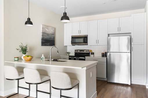 A kitchen with white cabinets and a stainless steel refrigerator.