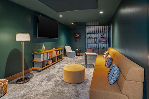 A living room with a couch, a chair, a floor lamp, a table, a TV, and a bookshelf.