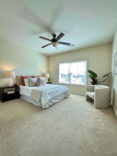 A bedroom with a bed, a chair, and a ceiling fan.
