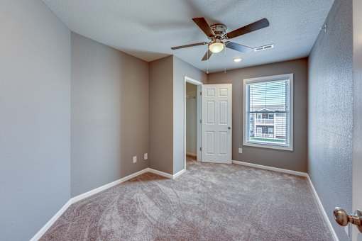 A room with a ceiling fan and carpeted floor.
