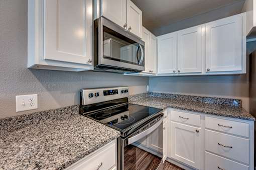 A kitchen with granite countertops and white cabinets.