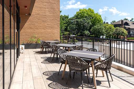A patio with tables and chairs is surrounded by a black fence.