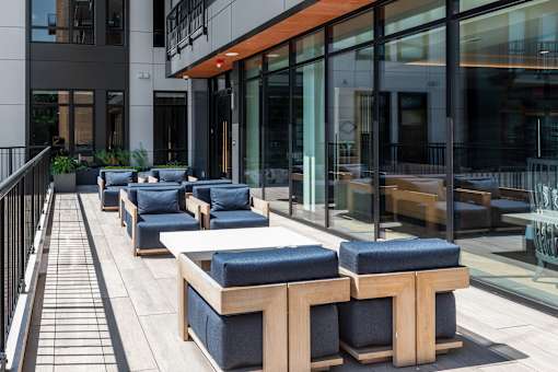 A patio with blue cushioned seating and a black railing.