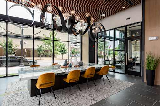 A modern dining room with a glass table and orange chairs.